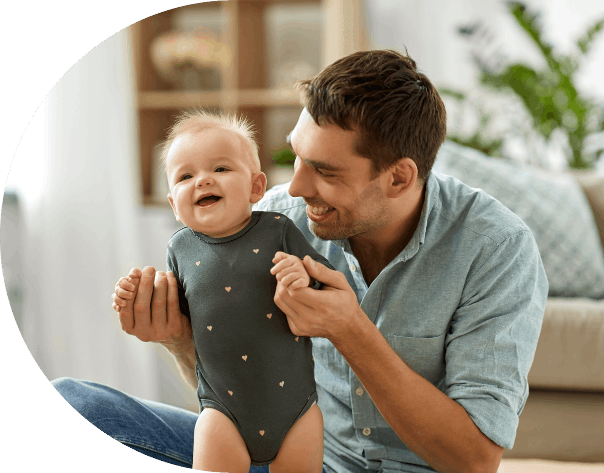 A smiling man lifting a laughing baby into the air
