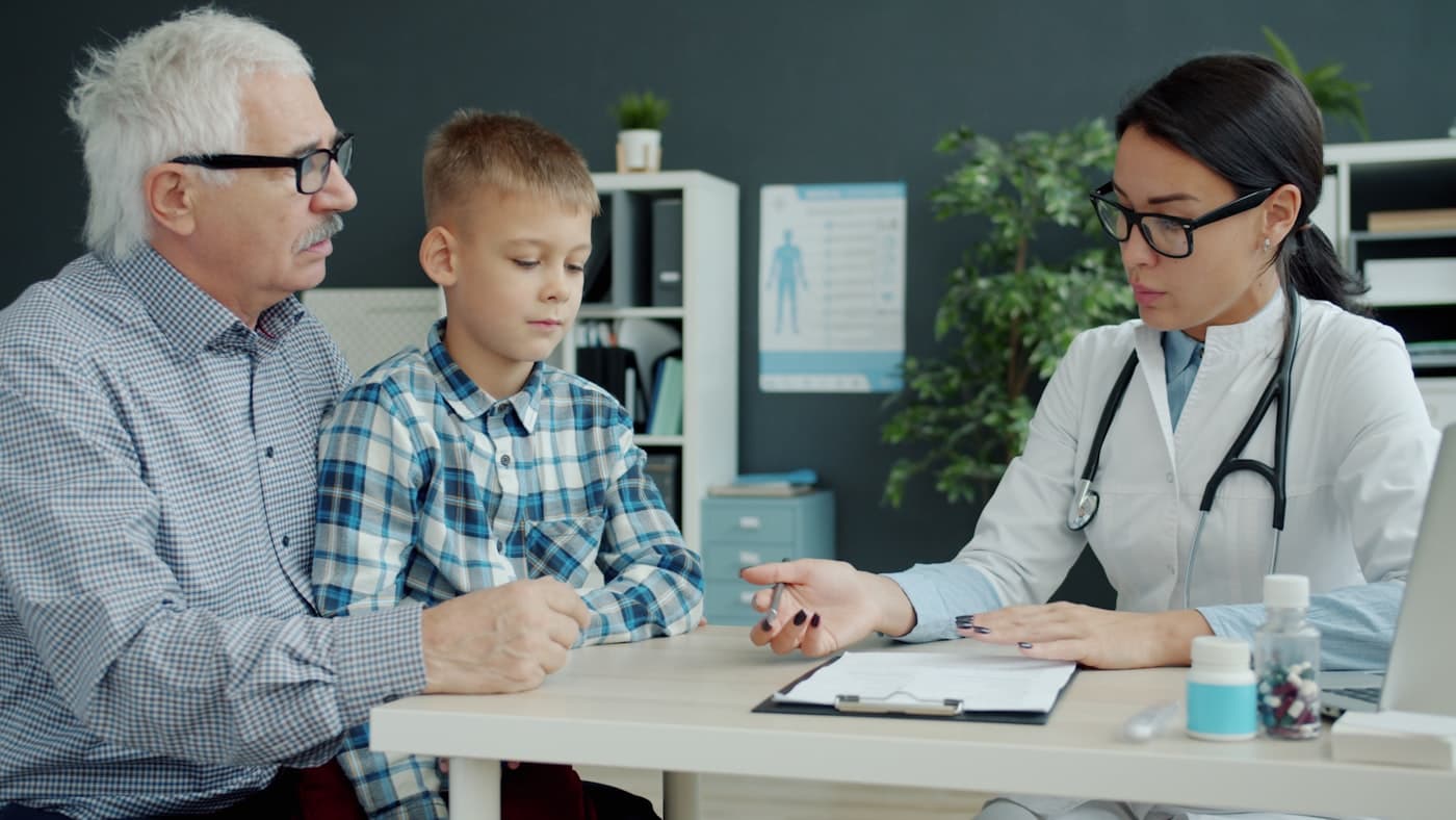 A doctor consulting with a grandfather and grandson in her office