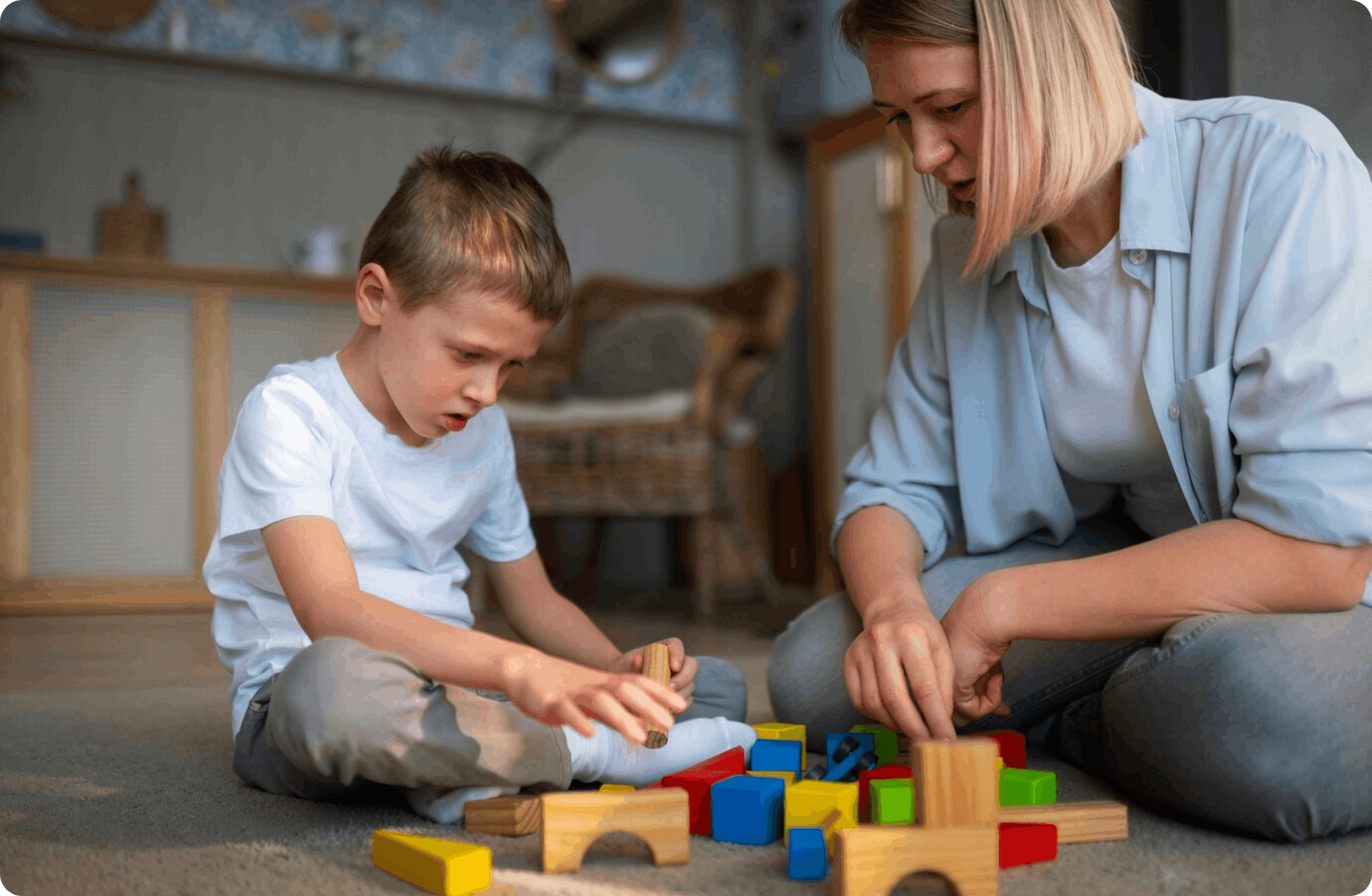 A woman and a young boy playing with colorful wooden building blocks on the floor